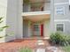 Inviting condo entrance with a red door, stone walkway, and manicured landscaping at 3034 Parkway Blvd # 102, Kissimmee, FL 34747