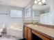 Bright bathroom with a soaking tub, vanity with a large mirror, and neutral-toned walls and tile at 3130 Clewiston St, Deltona, FL 32738