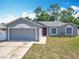 Charming single-story home features a gray exterior, attached garage, well-manicured lawn, and red front door at 3130 Clewiston St, Deltona, FL 32738