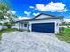 Beautiful home exterior features a blue garage door, paver driveway, manicured lawn, and decorative stone accents at 331 Erie Ct, Kissimmee, FL 34759