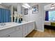 Bright bathroom featuring a double sink vanity, large mirror, and view to the bedroom at 4816 Tidecrest Ave # 178, Orlando, FL 32819
