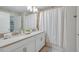 Modern bathroom with double sinks, white cabinets, and a shower with a white curtain at 4834 Lullaby Ln, Kissimmee, FL 34746