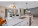 Modern kitchen island with quartz countertop, stainless steel appliances, and open floor plan with a living room and pool view at 4834 Lullaby Ln, Kissimmee, FL 34746