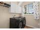 Well-equipped laundry room with black washer/dryer set and overhead storage cabinets at 490 Wekiva Preserve Dr, Apopka, FL 32712