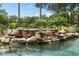 Screened pool with decorative rock waterfall, lush greenery, and a serene, tropical-inspired ambiance at 490 Wekiva Preserve Dr, Apopka, FL 32712