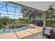 View of the screened-in pool with rock waterfall feature, set against the backdrop of the lake and lush landscaping at 490 Wekiva Preserve Dr, Apopka, FL 32712