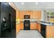 Galley kitchen features wood cabinets, black appliances, gray countertops, and modern gray flooring at 608 Ashwell Ct, Debary, FL 32713