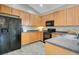 Galley kitchen features wood cabinets, black appliances, and gray countertops and flooring at 608 Ashwell Ct, Debary, FL 32713