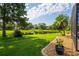 Lush backyard with pond view, mature trees, landscaped garden bed along the border at 641 Lakescape Ct, Orlando, FL 32828