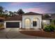 Charming single-story home with a two-car garage and inviting arched entryway at dusk at 641 Lakescape Ct, Orlando, FL 32828
