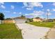 View of white single-story home with a long driveway and lawn at 657 Mckinley Ct, Kissimmee, FL 34758
