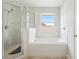 A bathtub and a shower behind a glass door are featured in this spacious bathroom at 670 Bluebill Ct, Poinciana, FL 34759