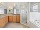 Bathroom with a glass-enclosed shower, large bathtub, and wooden cabinets at 670 Bluebill Ct, Poinciana, FL 34759