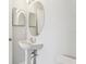 Small bathroom with a pedestal sink, toilet, and round mirror at 670 Bluebill Ct, Poinciana, FL 34759