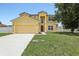 Two-story home with an attached two car garage, a large green lawn and blue skies at 670 Bluebill Ct, Poinciana, FL 34759