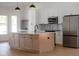 Kitchen island with light wood cabinets, marble countertops, white upper cabinets, and stainless steel appliances at 7646 Coconut Creek Ct, Orlando, FL 32822