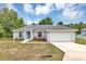 Charming single-story home with a well-maintained lawn, blue door, and attached two-car garage at 8 Water Trce, Ocala, FL 34472