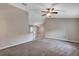 Open living room features a ceiling fan and neutral carpet flooring with tile flooring leading to kitchen area at 8 Water Trce, Ocala, FL 34472