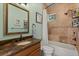 Bathroom featuring tiled shower-tub with bronze fixtures and granite countertop with decorative framed mirror at 1010 Juliette Blvd, Mount Dora, FL 32757