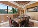 Elegant dining room featuring a wood table, leather chairs, chandelier, and a window with lush greenery views at 1010 Juliette Blvd, Mount Dora, FL 32757
