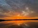 Scenic lake sunset featuring clouds with hues of gray, orange, and yellow reflected on the water at 1010 Juliette Blvd, Mount Dora, FL 32757