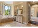 Luxurious main bathroom with a soaking tub, vanity area, and a large window overlooking lush greenery at 1010 Juliette Blvd, Mount Dora, FL 32757