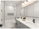 Elegant bathroom featuring dual sinks, gray cabinets, and a tub with a marble-tiled surround at 1113 Naples Dr, Orlando, FL 32804