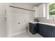 Laundry room featuring blue base cabinets, white uppers, a black hanging rod, and patterned flooring at 1113 Naples Dr, Orlando, FL 32804