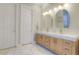 Bright bathroom with double vanity, wooden cabinetry, and large-format marble flooring at 11721 Camden Park Dr, Windermere, FL 34786