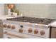 Close-up of kitchen gas stove with light green tiled backsplash and gold knobs and handle at 11721 Camden Park Dr, Windermere, FL 34786