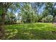 Large, grassy backyard shaded by mature trees leads to a pond with a fence at 120 Springwood Trl, Altamonte Springs, FL 32714