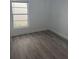 Cozy bedroom with gray wood-look laminate flooring, a window, and white trim at 1241 Cleveland Ave, Apopka, FL 32703