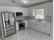Well-lit kitchen showcasing stainless steel appliances, white cabinetry, and a double basin sink under a window at 1241 Cleveland Ave, Apopka, FL 32703