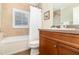 Bathroom features a bathtub, neutral tile, wood vanity, and a shower with a window that allows natural light into the room at 1355 Hibiscus Ave, Winter Park, FL 32789
