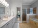 Bright bathroom featuring double sinks, large framed mirror, bathtub, and glassed-in shower at 1438 Stickley Ave, Celebration, FL 34747