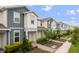 A row of modern townhouses with blue and white exteriors, landscaping and brick walkways at 14390 Orchid Island Dr, Orlando, FL 32827