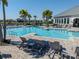 Community pool with lounge chairs and umbrellas, surrounded by palm trees and houses at 14390 Orchid Island Dr, Orlando, FL 32827