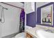 Clean bathroom with shower, tile surround, vanity with mirror, and bright purple accent wall at 1588 Alloway Dr, Deltona, FL 32738