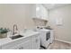 Modern laundry room with white cabinets, quartz countertops, a sink, and new washer and dryer at 2171 Timber Creek Ln, Clermont, FL 34715