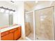 A bathroom with granite countertops, wooden cabinets, tile floors, and a glass enclosed shower at 2520 Bella Vista Dr, Davenport, FL 33897
