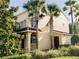 Inviting tan townhome boasting a balcony, palm trees, and lush greenery, creating a tropical and serene atmosphere at 2520 Bella Vista Dr, Davenport, FL 33897