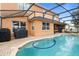Screened in in-ground pool with brick patio, attached hot tub, and outdoor cooking area at 314 Edgewood Ct, Kissimmee, FL 34759