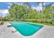 Backyard pool with a concrete deck is surrounded by lush landscaping and a wooden fence at 320 Bridle Path, Casselberry, FL 32707