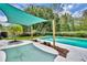 Backyard pool featuring a sun shade, landscaping, and concrete pool deck in a private backyard at 320 Bridle Path, Casselberry, FL 32707