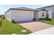 Home featuring a brick driveway, attached two-car garage, and professionally landscaped front yard at 3253 Viceroy Ct, Poinciana, FL 34759