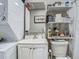 Efficient bathroom featuring a toilet, sink, stacked washer/dryer, mirror and white shelving at 3325 Horseshoe Dr, Longwood, FL 32779