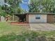 View of back of property with recreational playset, brick, white board and batten, mulched patio and corrugated cover at 3325 Horseshoe Dr, Longwood, FL 32779