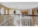 Upstairs hallway featuring wood railing, arched windows, and natural lighting at 3656 Heirloom Rose Pl, Oviedo, FL 32766