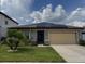 Charming single-Gathering house with a tan garage, lush green lawn, and solar panels, blending comfort with sustainability at 398 Citrus Isle Loop, Davenport, FL 33837