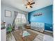 Bright Bedroom featuring a crib, changing table, playful rug, and a blue accent wall at 3980 Gadwall Pl, Leesburg, FL 34748
